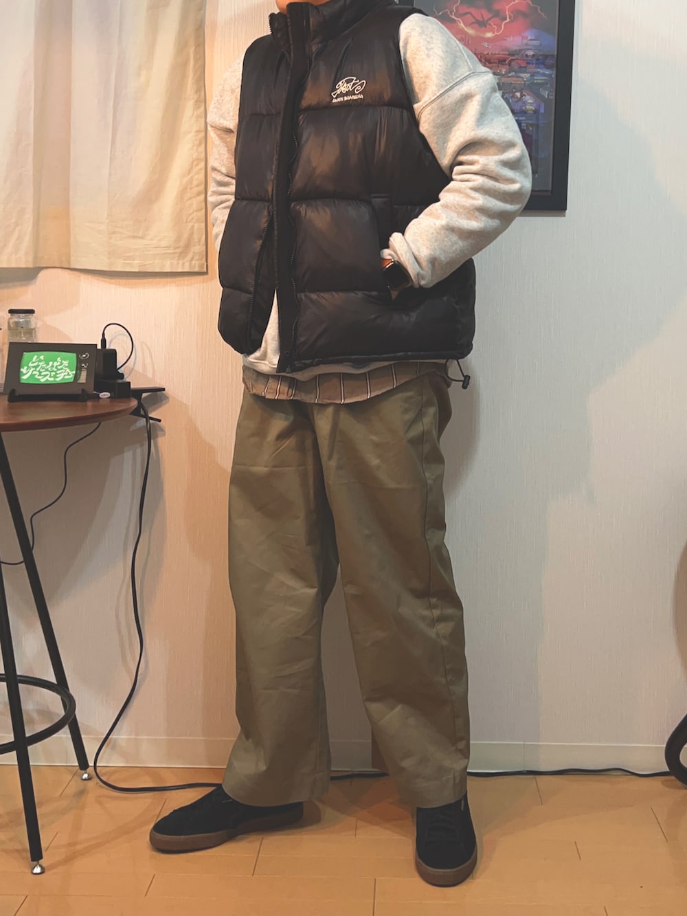 ブラック系のダウンベスト、グレー系のTシャツ/カットソー、ベージュ系のチノパンツを着用したメンズの冬コーディネートの3枚目の写真