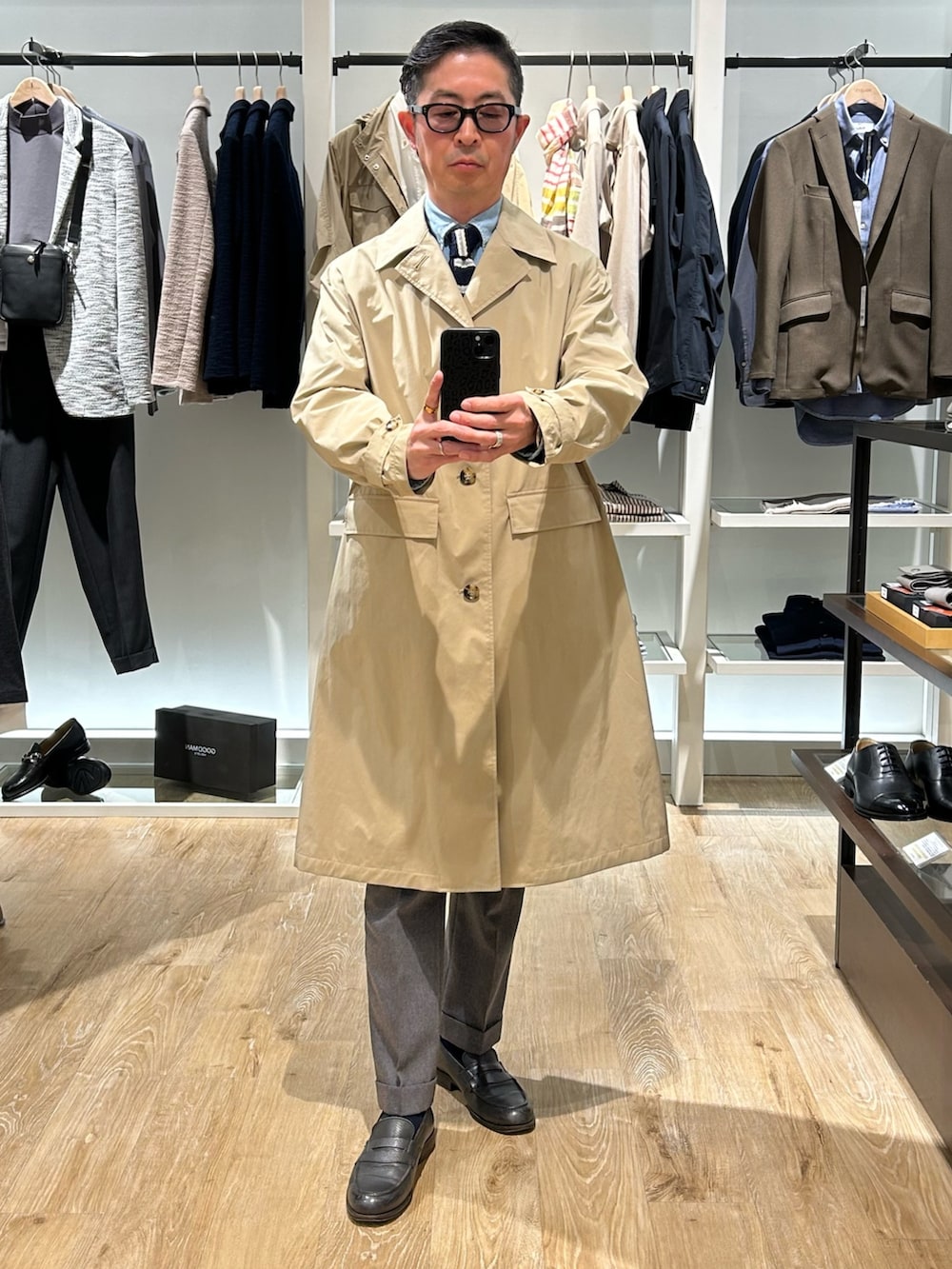 ベージュ系のステンカラーコート、ブルー系のテーラードジャケットを着用したメンズの冬コーディネートの2枚目の写真