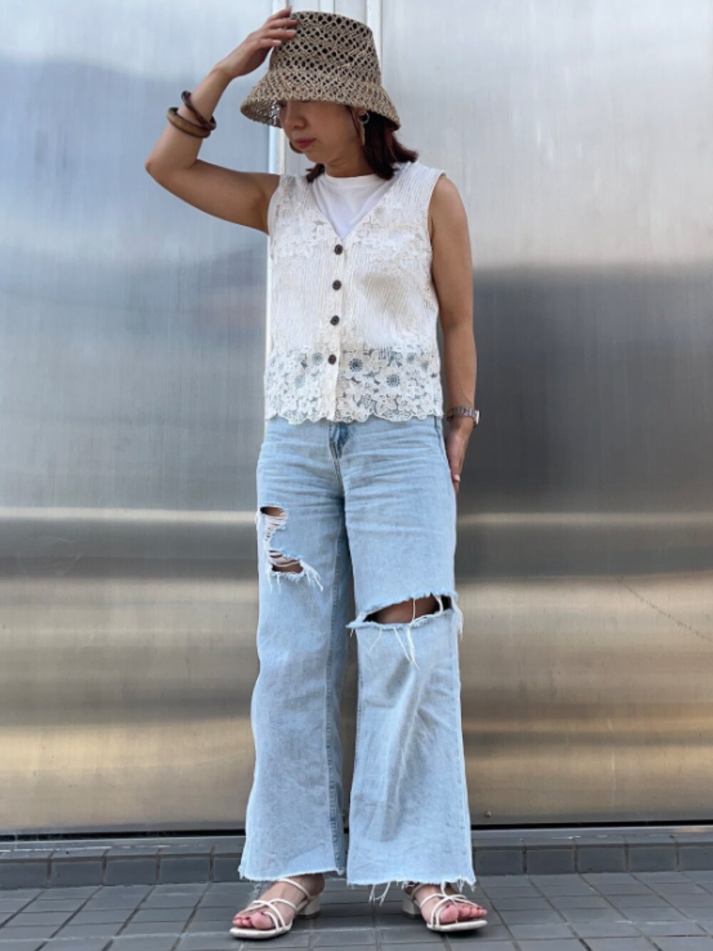 ブルー系のデニムパンツ、ホワイト系のベスト、ベージュ系の帽子を着用したレディースの夏コーディネートの2枚目の写真