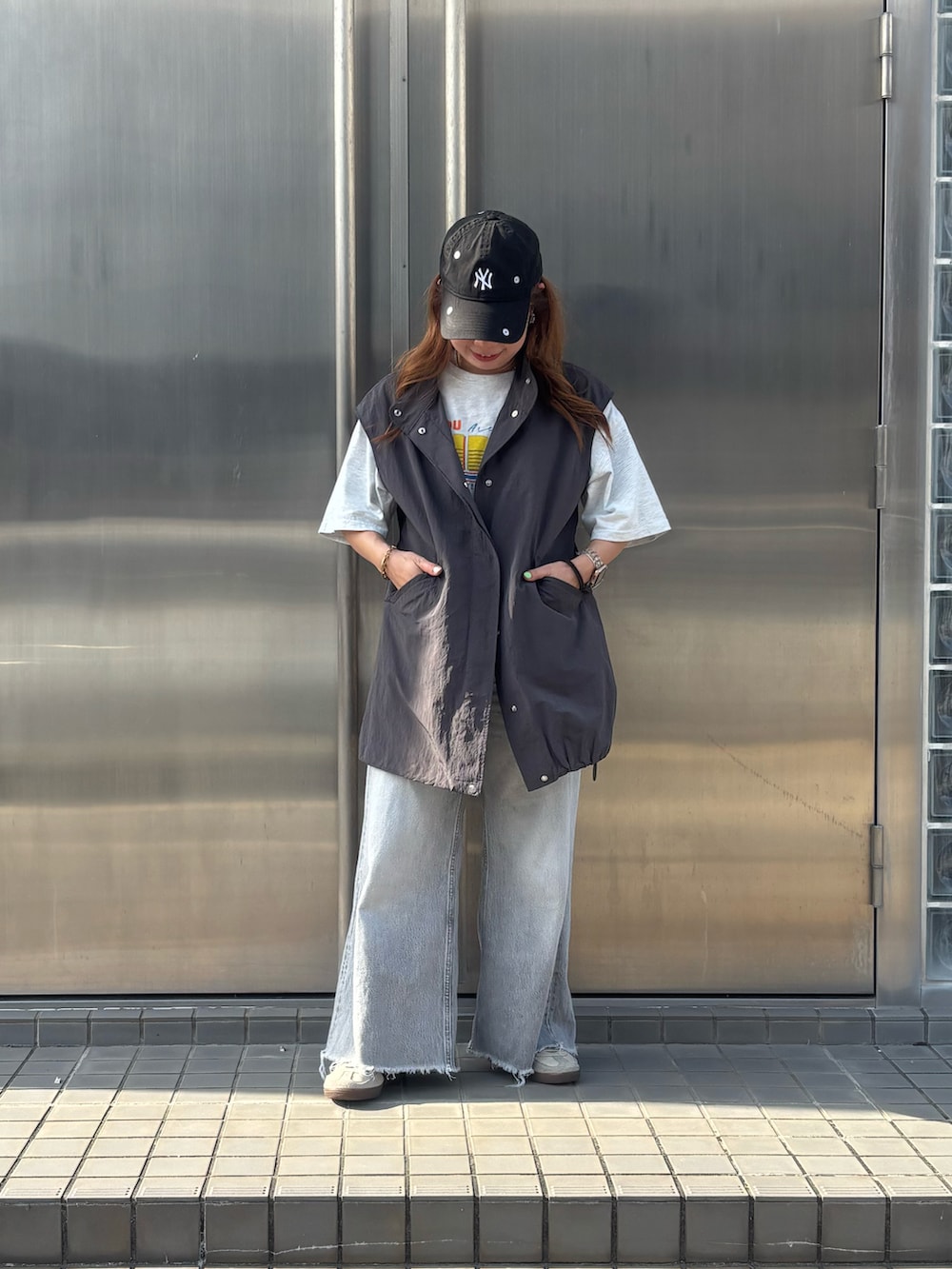 グレー系のベスト、グレー系のTシャツ/カットソー、グレー系のデニムパンツを着用したレディースの春コーディネートの2枚目の写真