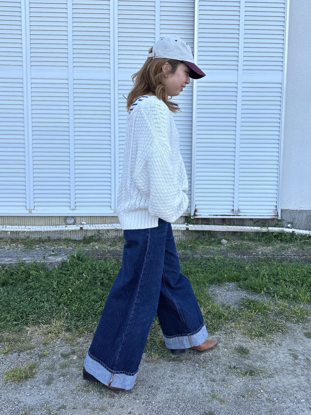 ブルー系のデニムパンツ、ホワイト系のニット/セーター、ブルー系のTシャツ/カットソーを着用したレディースの春コーディネートの2枚目の写真