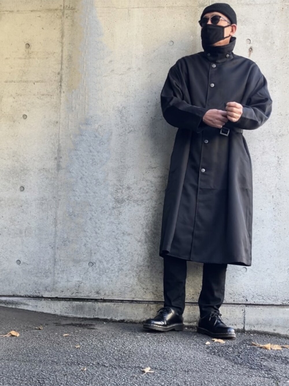 ブラック系のステンカラーコート、ブラック系のデニムパンツ、ブラック系のその他シューズを着用したメンズの冬コーディネートの3枚目の写真