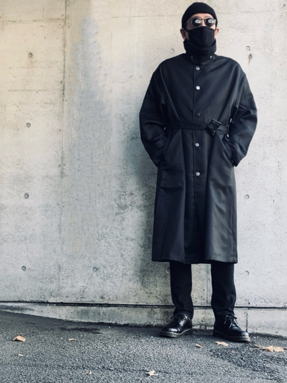 ブラック系のステンカラーコート、ブラック系のデニムパンツ、ブラック系のその他シューズを着用したメンズの冬コーディネートの2枚目の写真