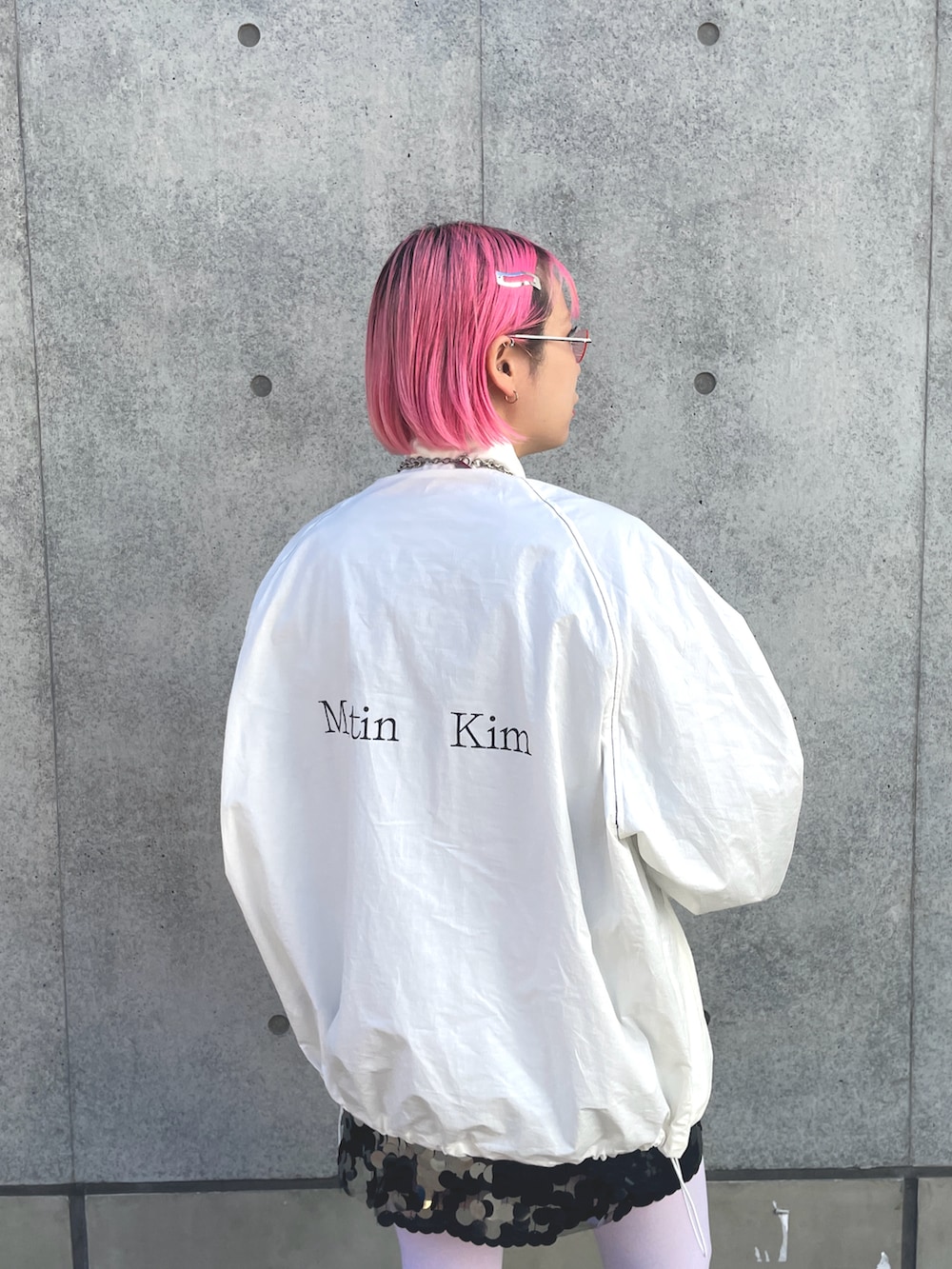 ホワイト系のナイロンジャケット、シルバー系のスカート、ブラック系のバレエシューズを着用したレディースの冬コーディネートの2枚目の写真