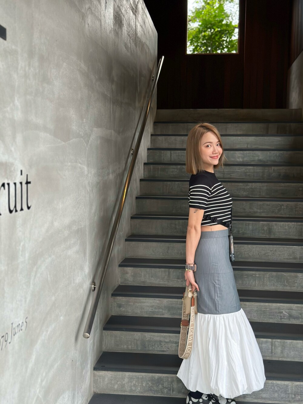 ブルー系のスカート、ベージュ系のバッグ、ブラック系のローファーを着用したレディースの冬コーディネートの3枚目の写真