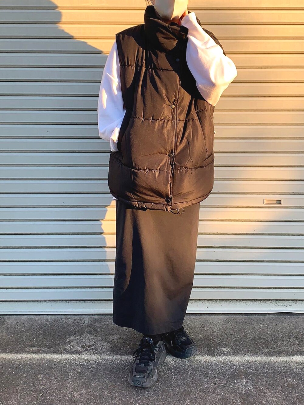 ブラック系のダウンベスト、ホワイト系のTシャツ/カットソー、ブラック系のスニーカーを着用したレディースの秋コーディネートの3枚目の写真