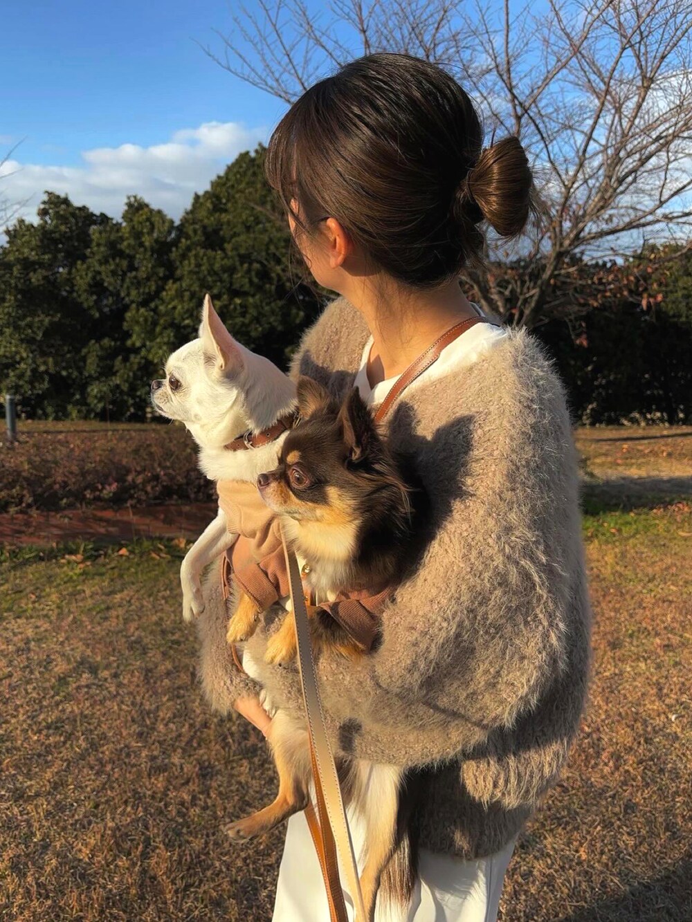 ベージュ系のニット/セーター、ホワイト系のスラックスを着用したレディースの冬コーディネートの2枚目の写真