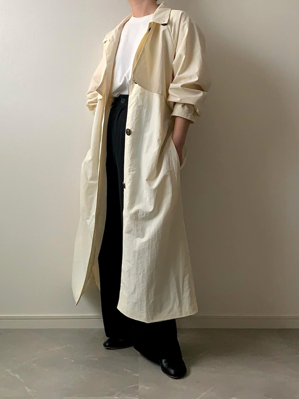 ホワイト系のトレンチコート、ブラック系のハンドバッグを着用したレディースの春コーディネートの2枚目の写真