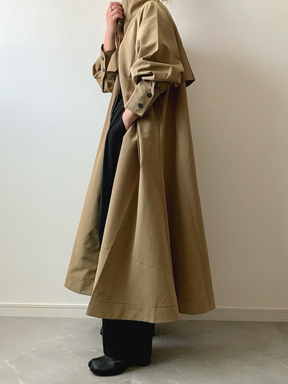 ベージュ系のトレンチコートを着用したレディースの秋コーディネートの2枚目の写真
