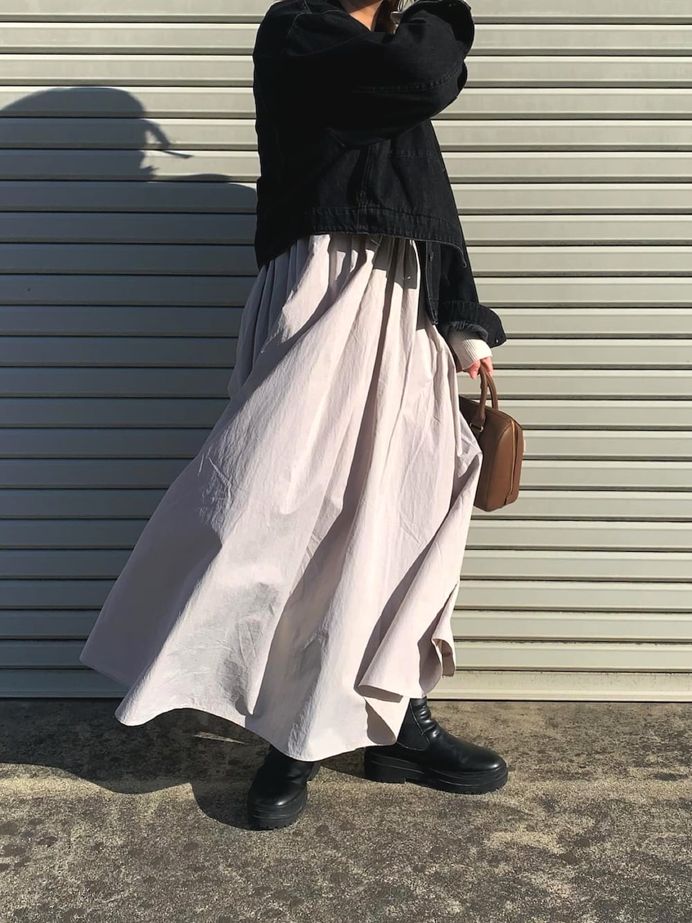 グレー系のワンピース、ブラック系のデニムジャケット、ブラウン系のバッグを着用したレディースの春コーディネートの2枚目の写真