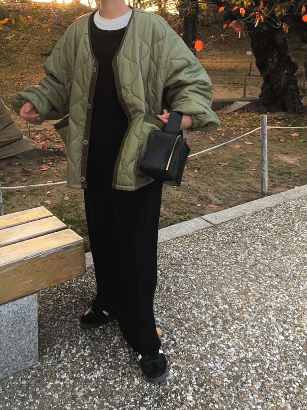 グリーン系のノーカラージャケット、ブラック系のワンピースを着用したレディースの秋コーディネートの2枚目の写真