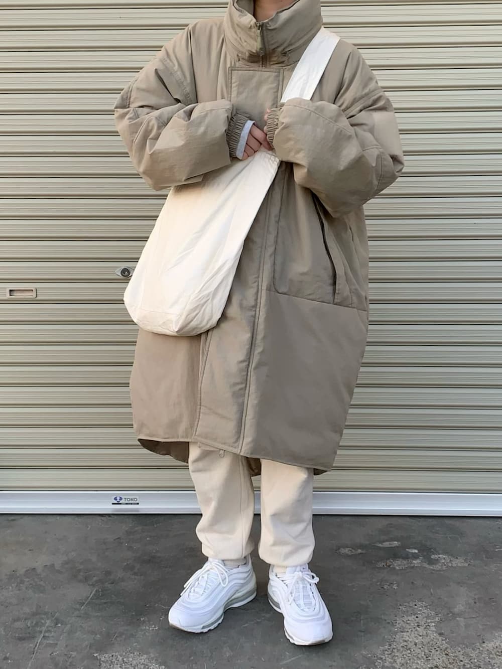 グリーン系のダウンジャケット/コート、ホワイト系のショルダーバッグ、ホワイト系のスニーカーを着用したレディースの冬コーディネートの2枚目の写真