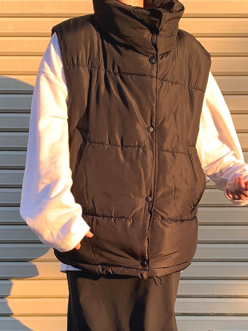 ブラック系のダウンベスト、ホワイト系のTシャツ/カットソー、ブラック系のスニーカーを着用したレディースの秋コーディネートの2枚目の写真