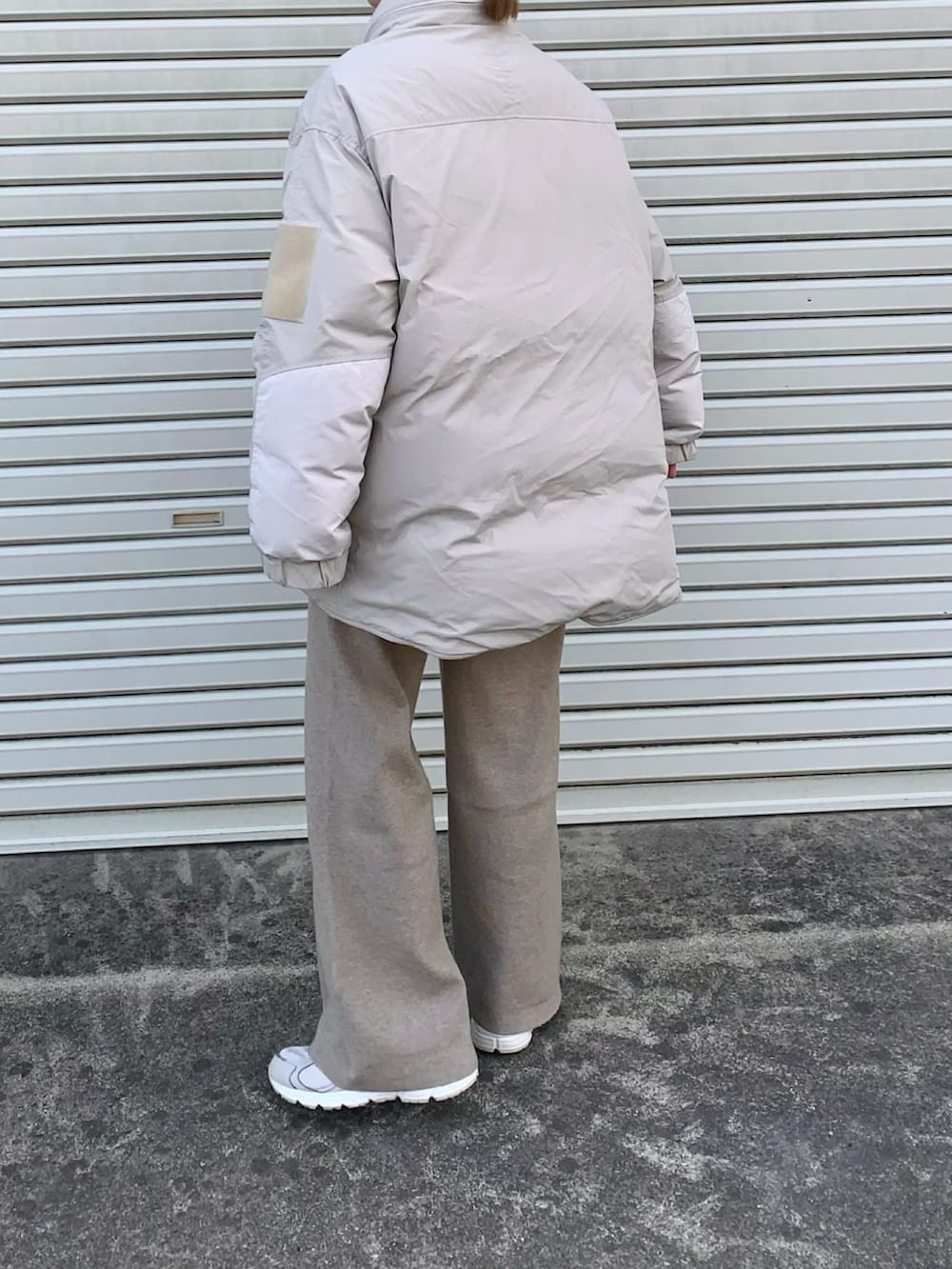 ベージュ系のその他パンツ、グレー系のダウンジャケット/コート、ホワイト系のスニーカーを着用したレディースの冬コーディネートの2枚目の写真