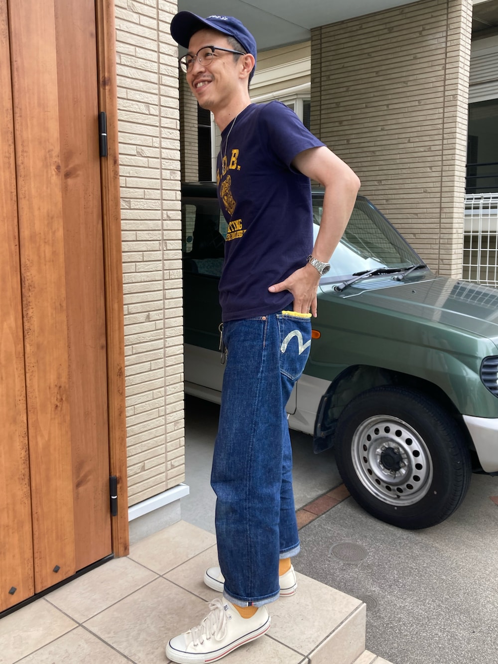 ブルー系のTシャツ/カットソー、ブルー系のデニムパンツ、ベージュ系のスニーカーを着用したメンズの夏コーディネートの2枚目の写真