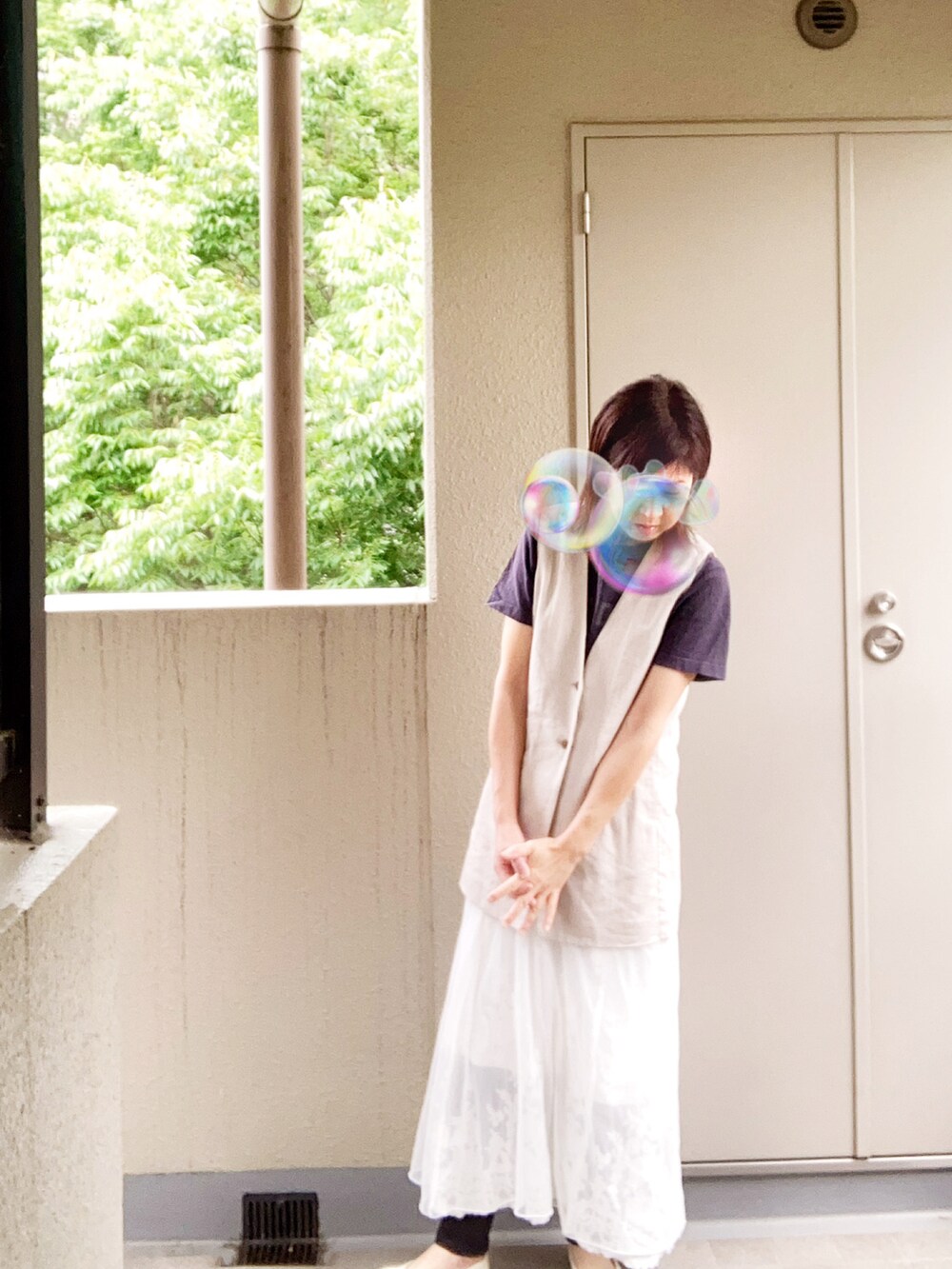 ベージュ系のノーカラージャケット、ホワイト系のスカートを着用したレディースの夏コーディネートの2枚目の写真