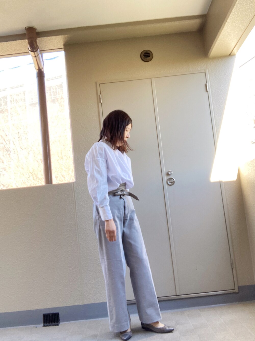 グレー系のデニムパンツ、ホワイト系のシャツ/ブラウス、シルバー系のパンプスを着用したレディースの冬コーディネートの2枚目の写真