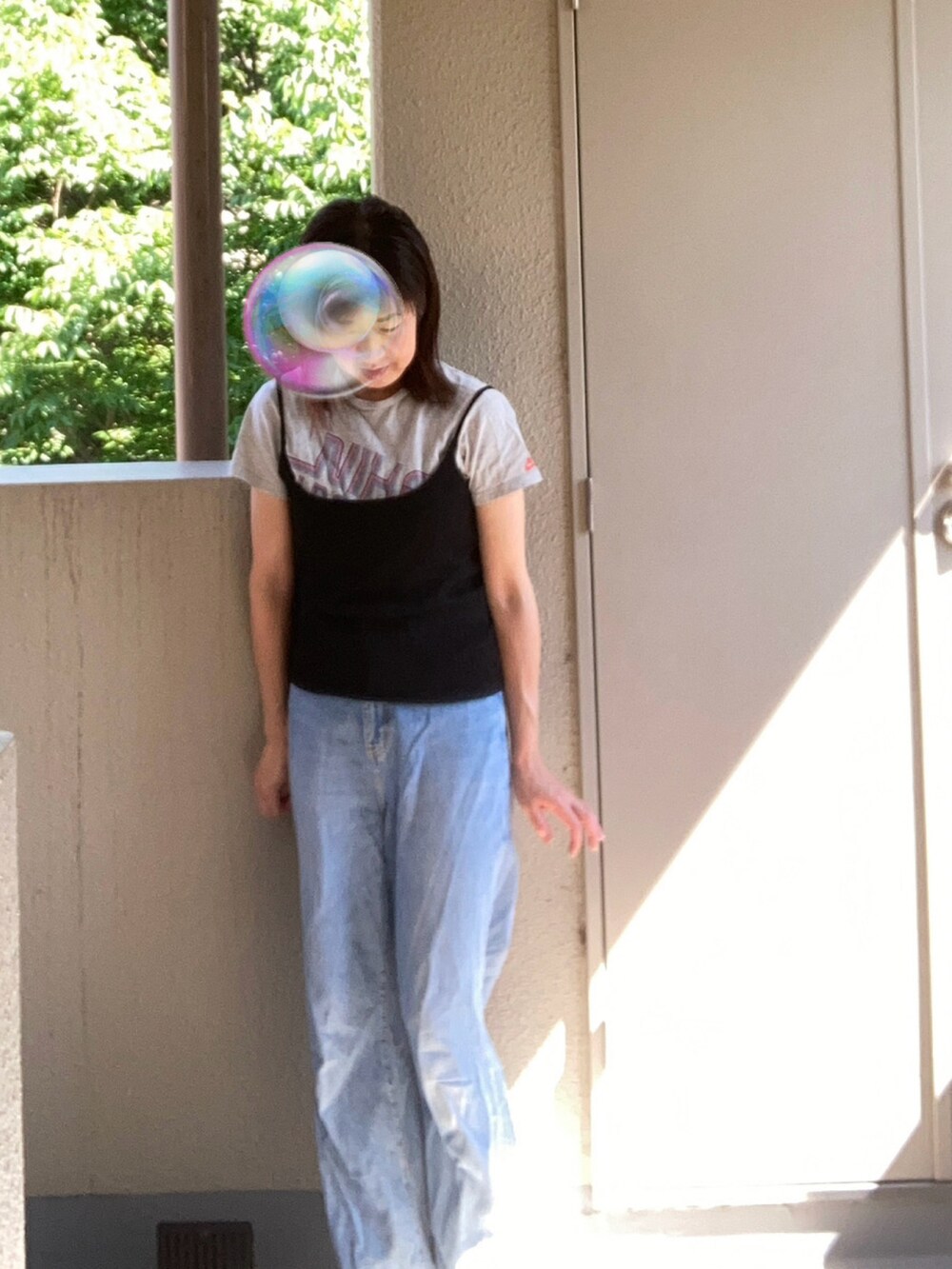 グレー系のTシャツ/カットソー、ブラック系のキャミソール、ブルー系のデニムパンツを着用したレディースの夏コーディネートの2枚目の写真