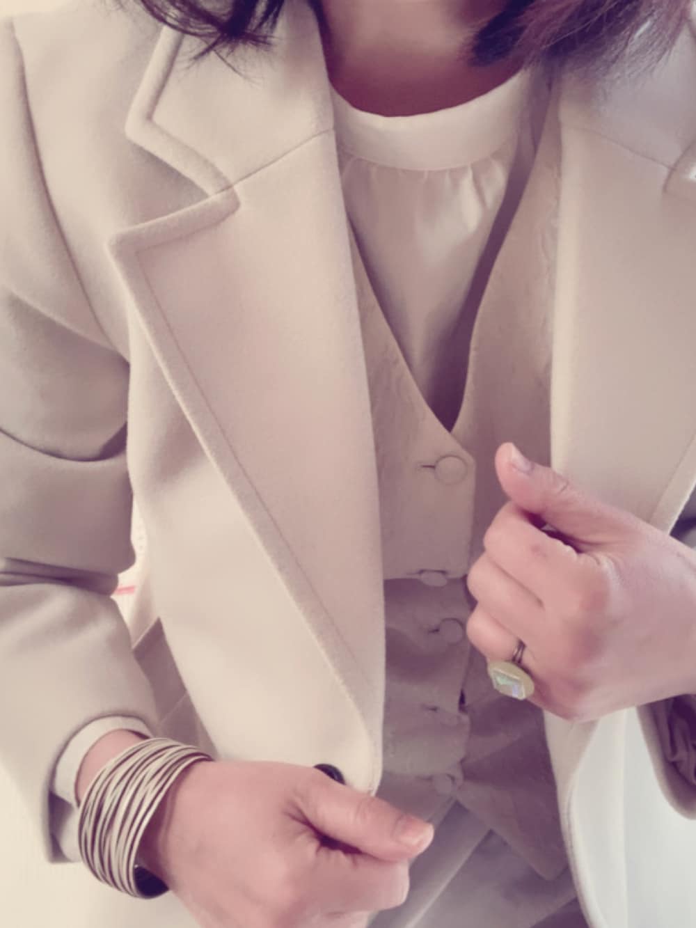 ホワイト系のチェスターコート、ベージュ系のベスト、ホワイト系のシャツ/ブラウスを着用したレディースの冬コーディネートの2枚目の写真