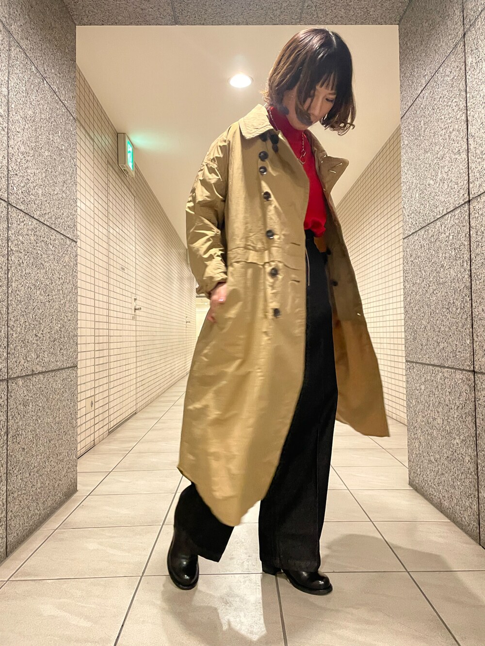 レッド系のニット/セーター、ブラック系のデニムパンツ、ブラック系のブーツを着用したレディースの冬コーディネートの3枚目の写真