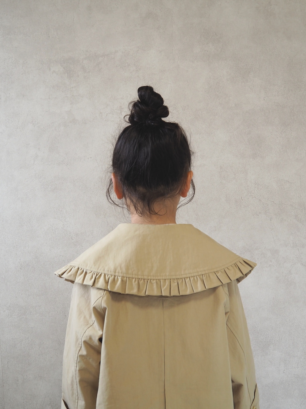 ピンク系のTシャツ/カットソー、ベージュ系のステンカラーコート、ブラック系のスニーカーを着用したキッズの冬コーディネートの5枚目の写真