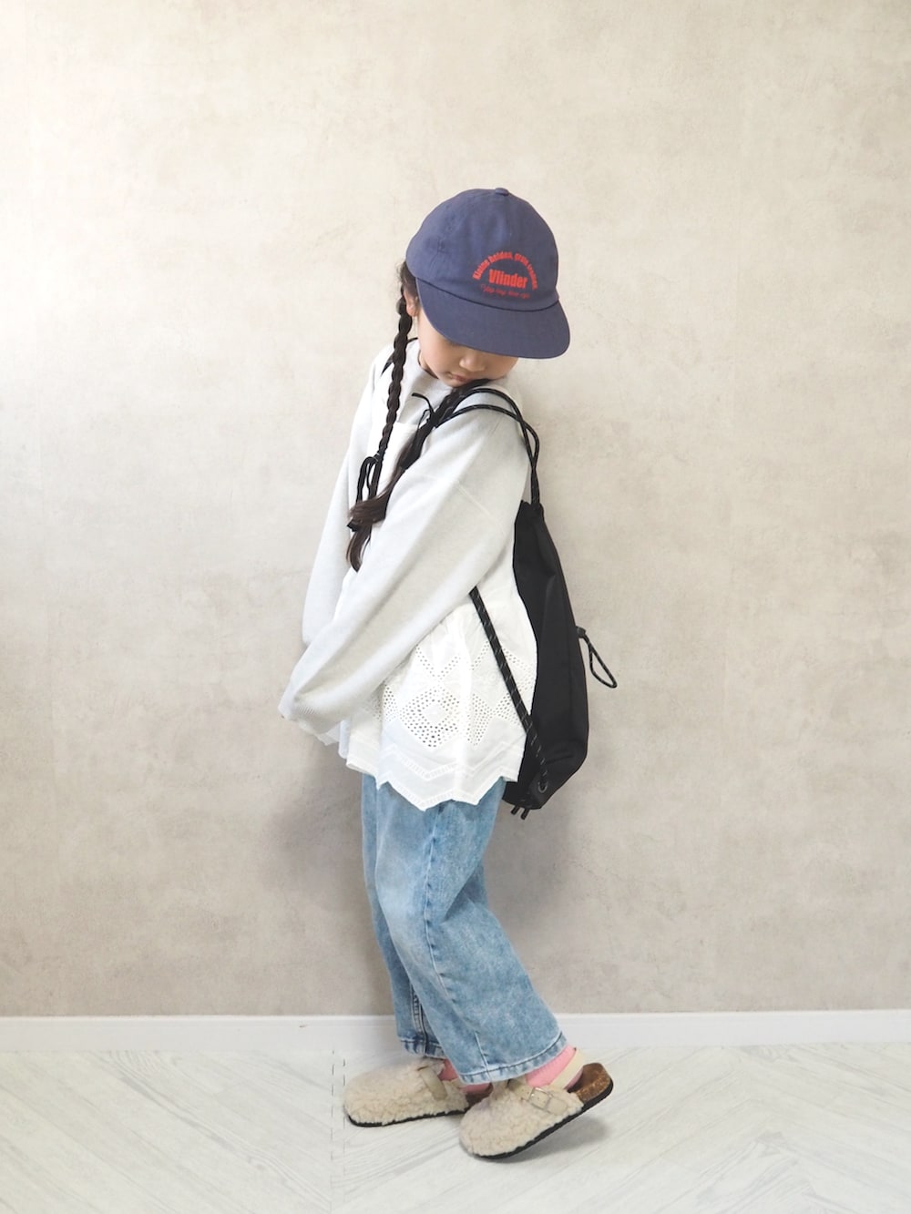 ホワイト系のニット/セーター、ホワイト系のサンダル、ブラック系のバックパック/リュックを着用したキッズの冬コーディネートの2枚目の写真