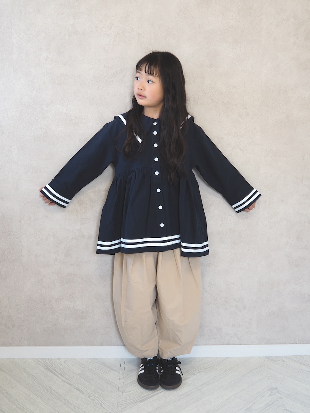 ブルー系のワンピース、ブラック系のスニーカー、ベージュ系のその他パンツを着用したキッズの春コーディネートの2枚目の写真