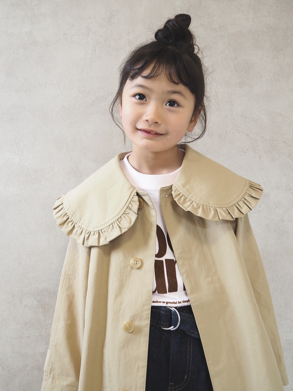 ピンク系のTシャツ/カットソー、ベージュ系のステンカラーコート、ブラック系のスニーカーを着用したキッズの冬コーディネートの4枚目の写真