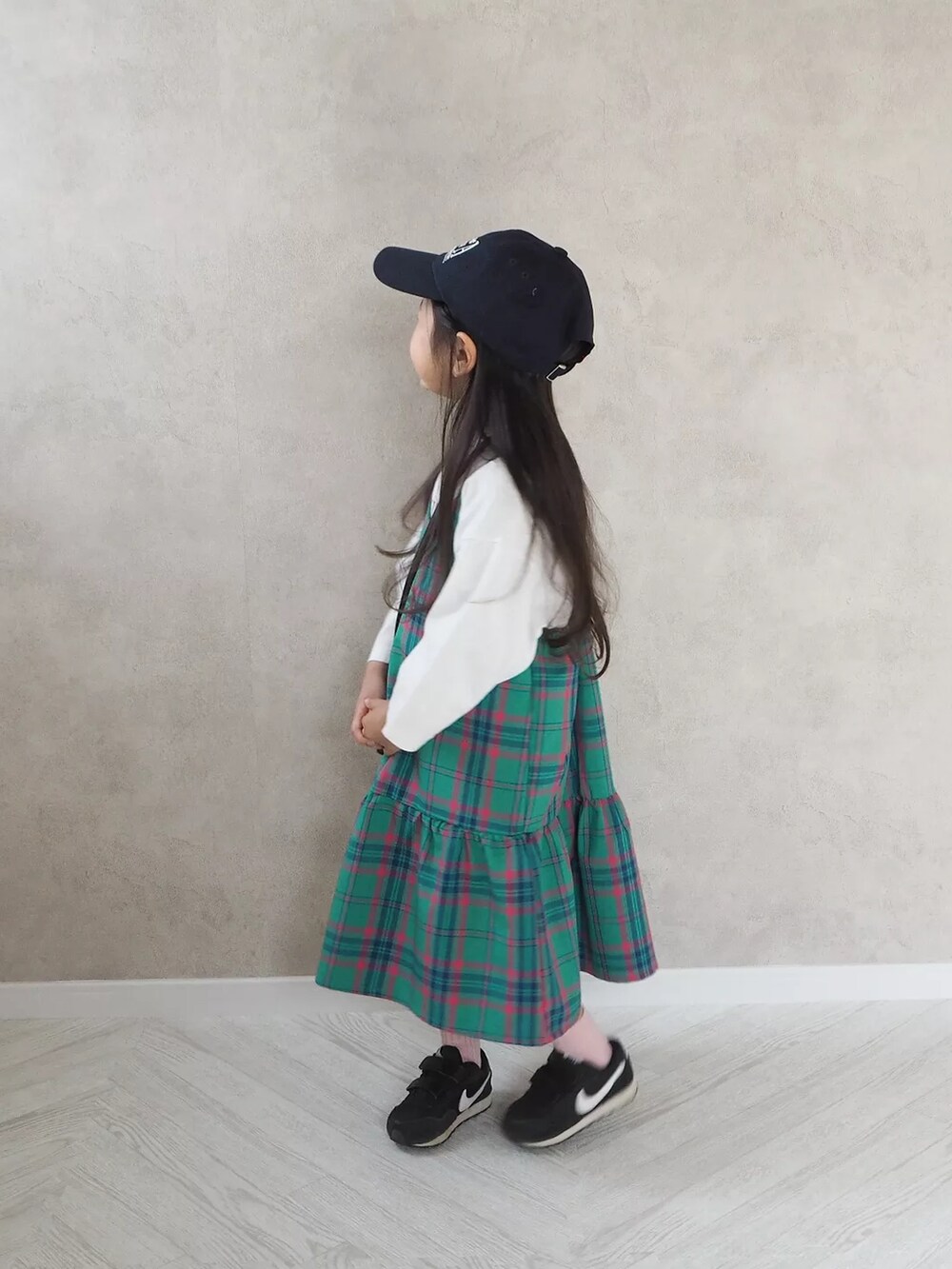 ブラック系のショルダーバッグ、グリーン系のワンピース、ブラック系のスニーカーを着用したキッズの春コーディネートの2枚目の写真