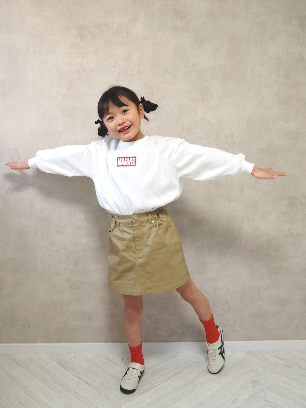 ベージュ系のスカート、ホワイト系のTシャツ/カットソー、ホワイト系のスニーカーを着用したキッズの冬コーディネートの2枚目の写真