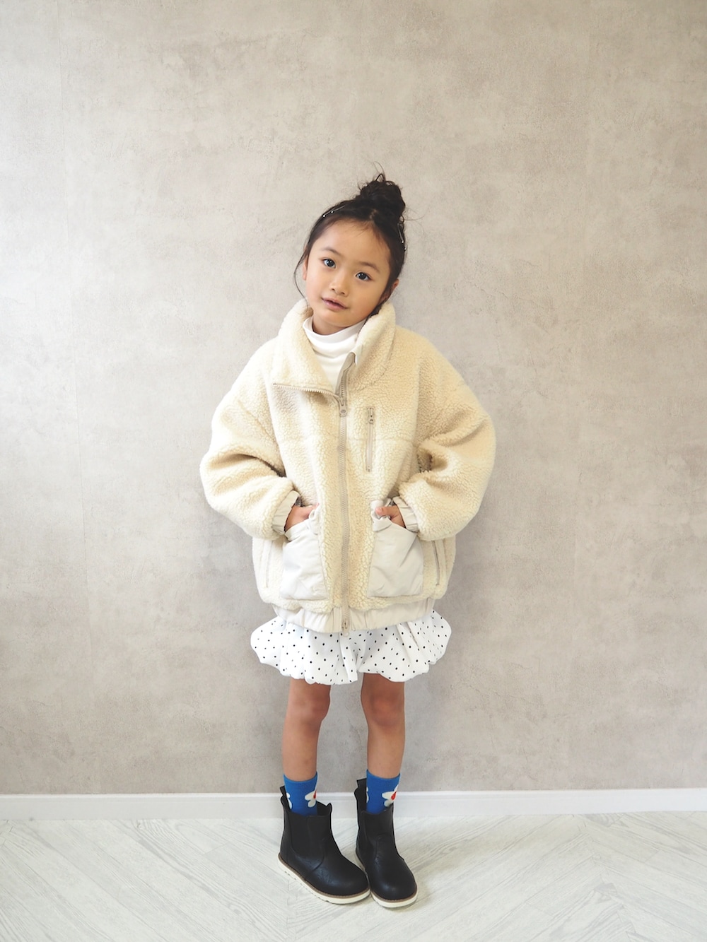 ホワイト系のブルゾン、ホワイト系のスカート、ホワイト系のTシャツ/カットソーを着用したキッズの冬コーディネートの2枚目の写真