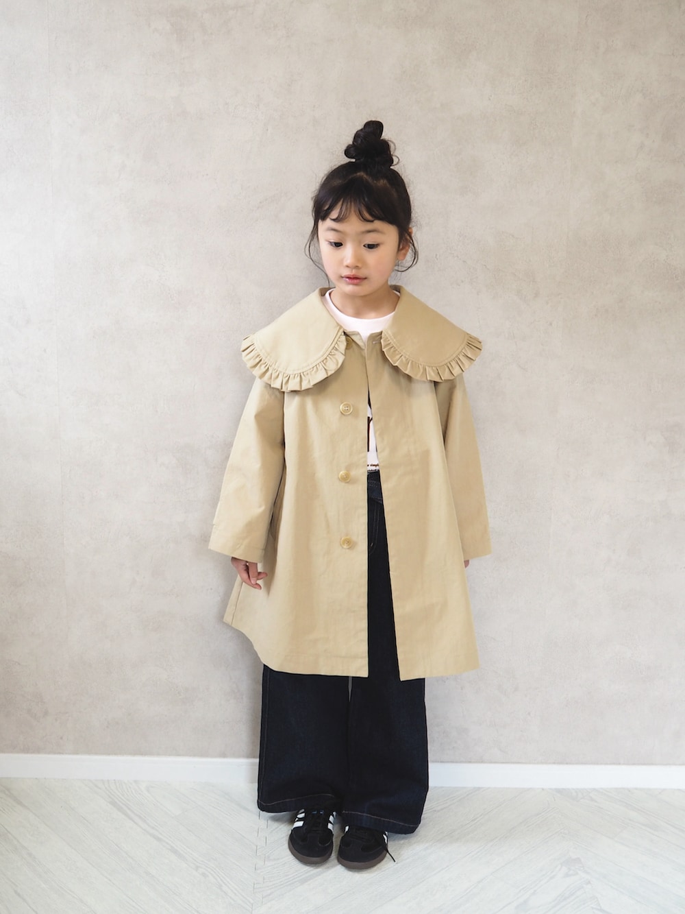 ピンク系のTシャツ/カットソー、ベージュ系のステンカラーコート、ブラック系のスニーカーを着用したキッズの冬コーディネートの3枚目の写真