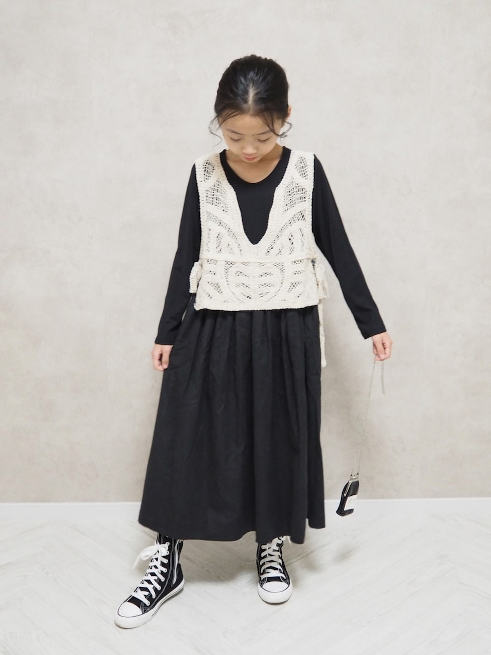 ブラック系のワンピース、ベージュ系のベスト、ブラック系の財布を着用したキッズの秋コーディネートの2枚目の写真