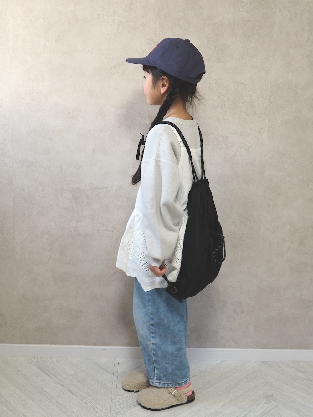 ホワイト系のニット/セーター、ホワイト系のサンダル、ブラック系のバックパック/リュックを着用したキッズの冬コーディネートの4枚目の写真