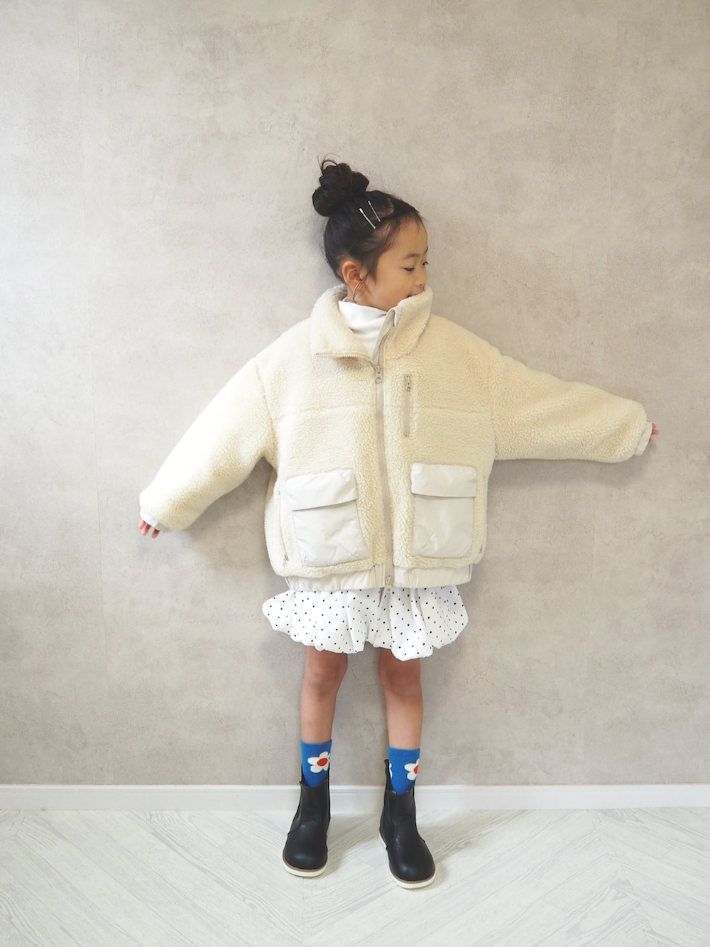ホワイト系のブルゾン、ホワイト系のスカート、ホワイト系のTシャツ/カットソーを着用したキッズの冬コーディネートの3枚目の写真