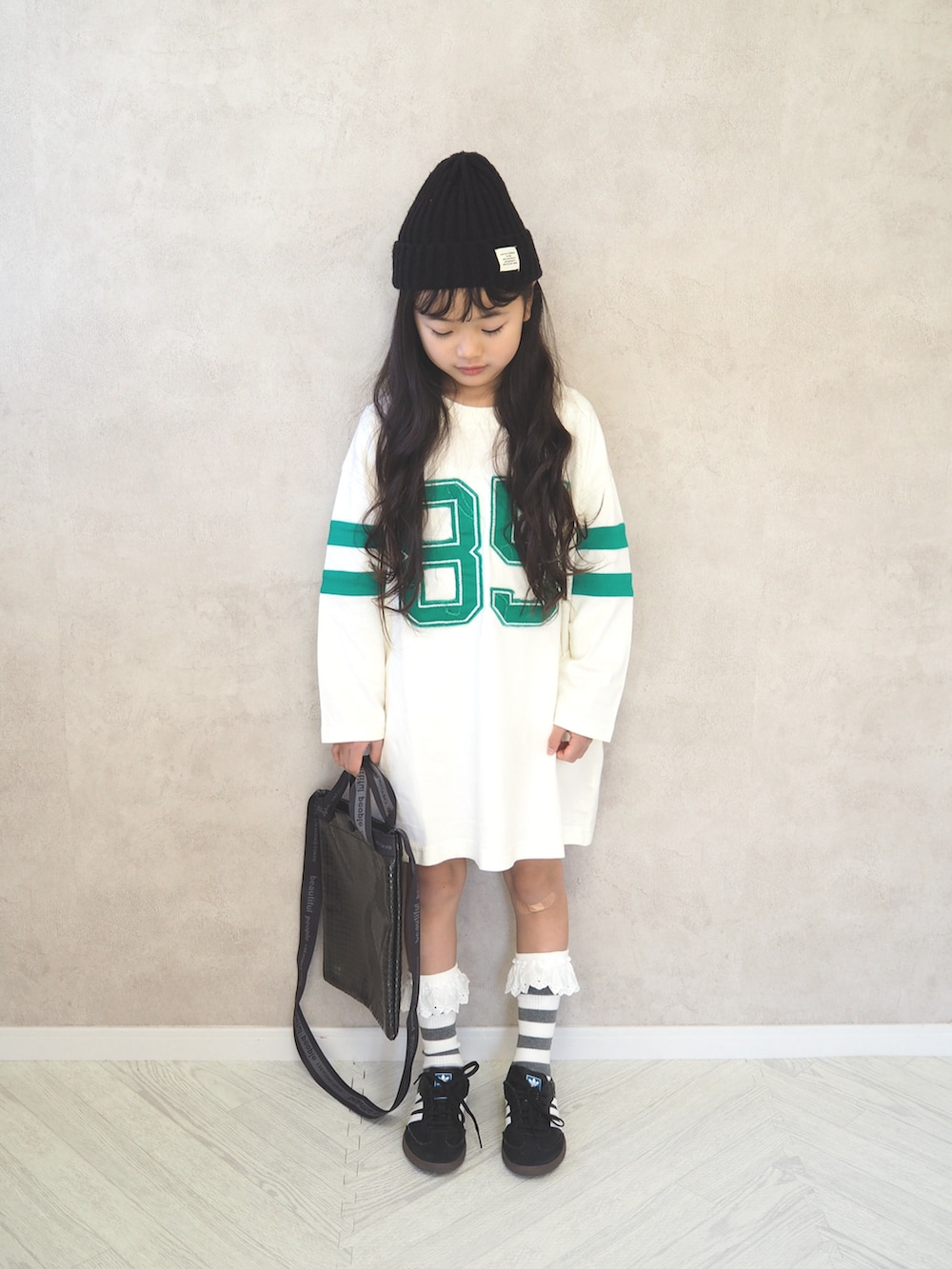 ブラック系のスニーカー、ホワイト系のワンピース、ブラック系のショルダーバッグを着用したキッズの冬コーディネートの2枚目の写真
