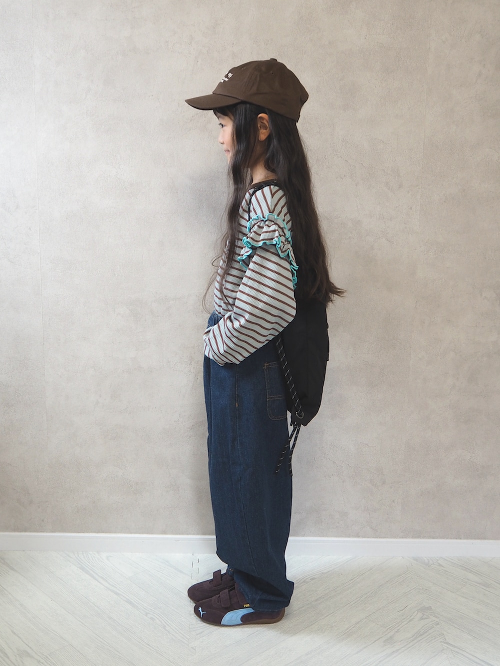ブラック系のバックパック/リュック、グリーン系のTシャツ/カットソー、ブルー系のデニムパンツを着用したキッズの秋コーディネートの3枚目の写真
