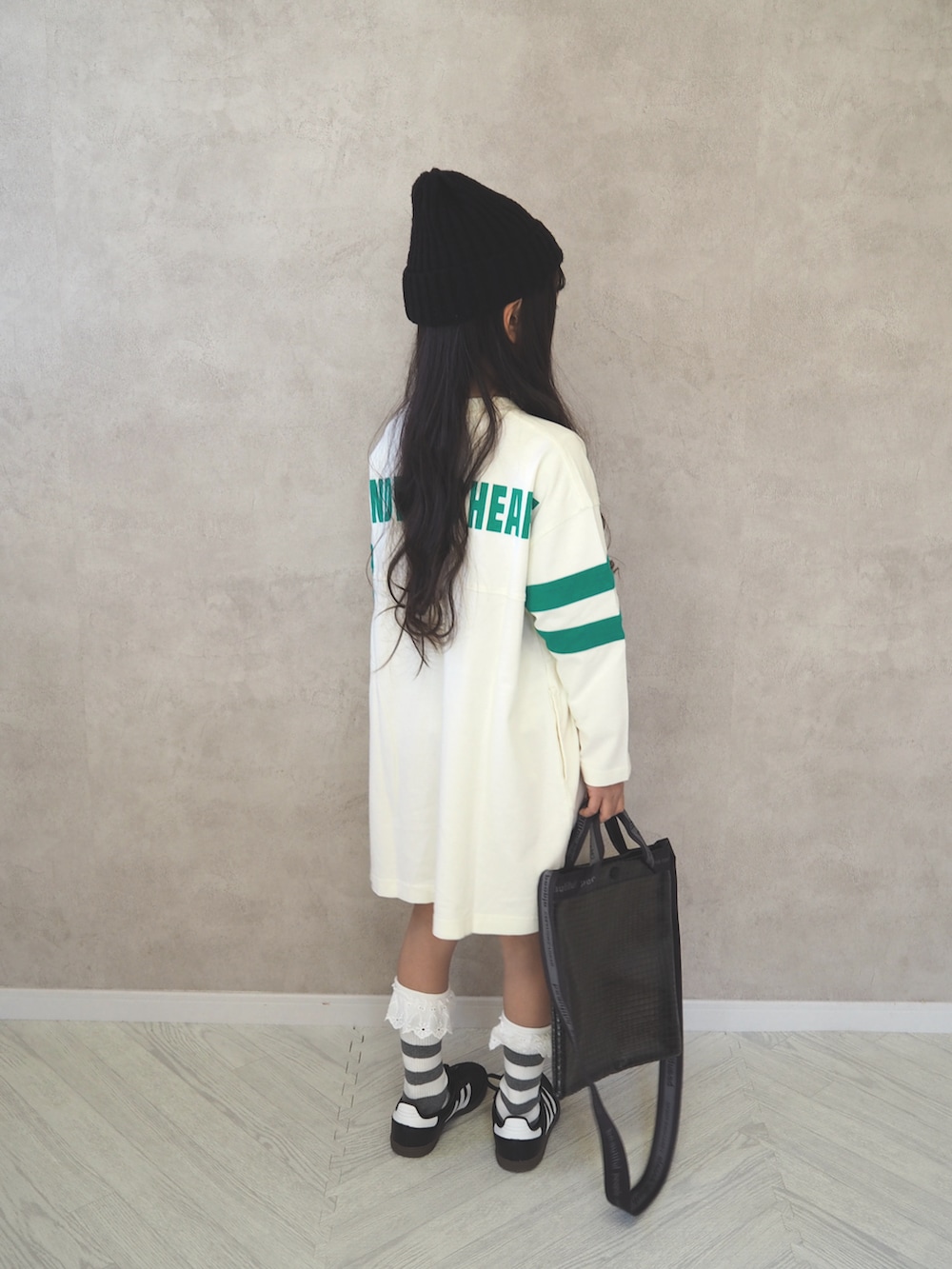 ブラック系のスニーカー、ホワイト系のワンピース、ブラック系のショルダーバッグを着用したキッズの冬コーディネートの3枚目の写真