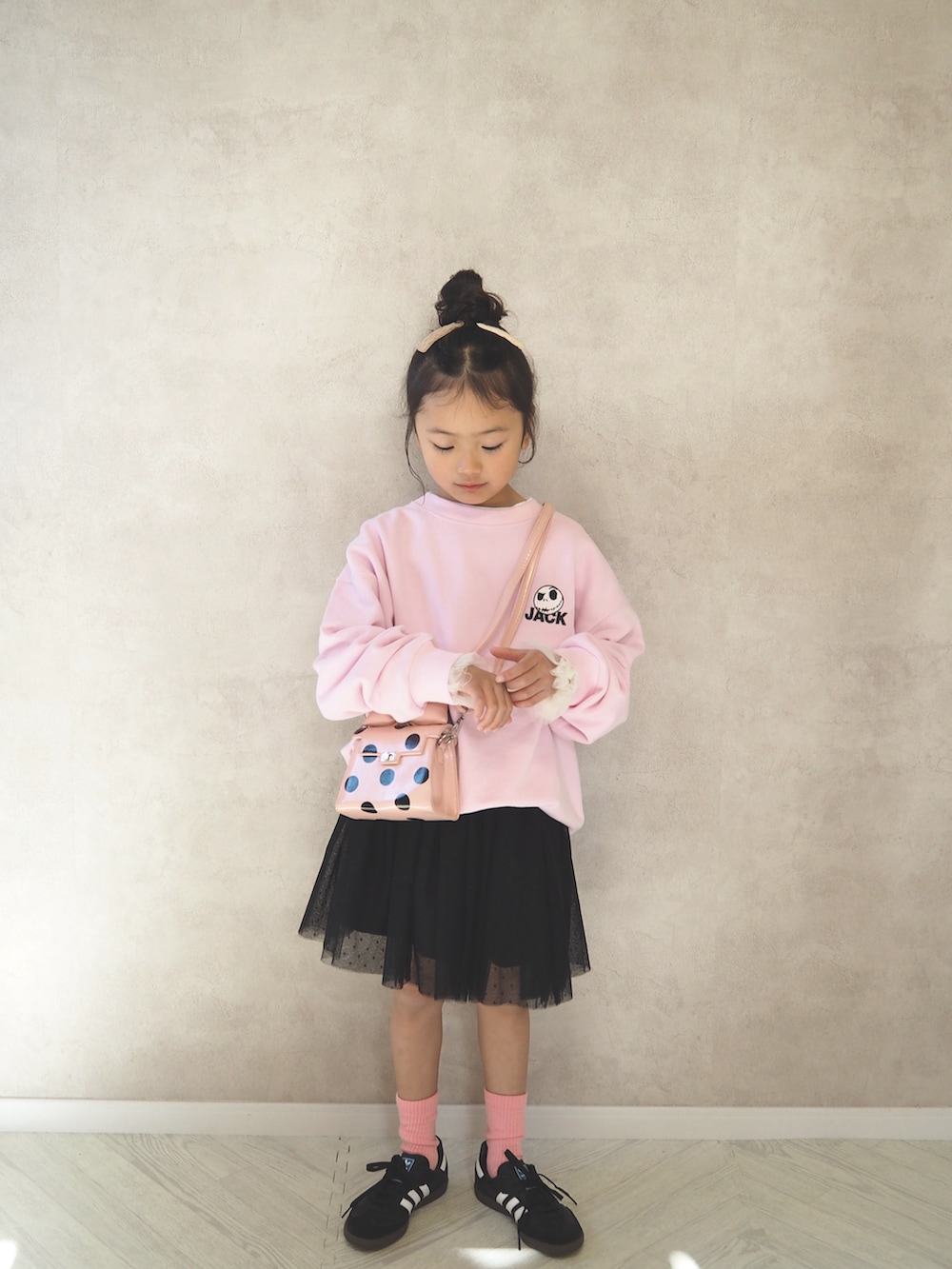 ピンク系のスウェット、ピンク系のショルダーバッグ、ブラック系のスカートを着用したキッズの冬コーディネートの3枚目の写真