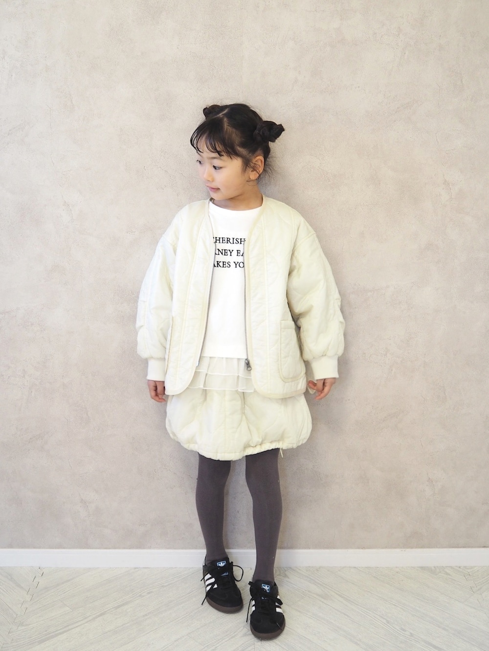 ブラック系のスニーカー、ホワイト系のミリタリージャケット、ホワイト系のスカートを着用したキッズの冬コーディネートの3枚目の写真