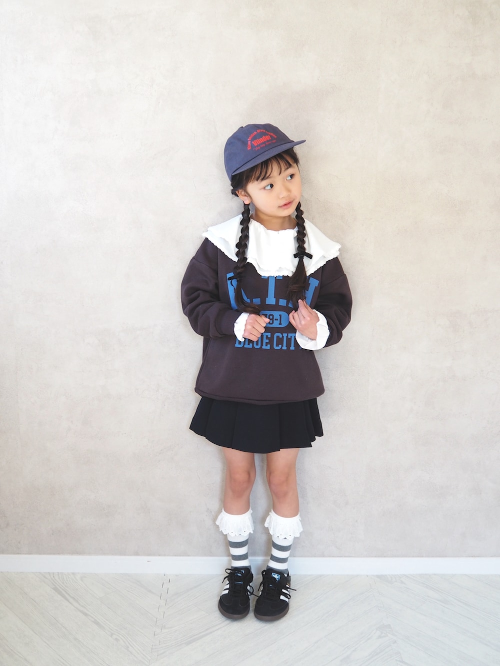 ブラウン系のスウェット、ホワイト系のシャツ/ブラウス、ブルー系のスカートを着用したキッズの冬コーディネートの2枚目の写真