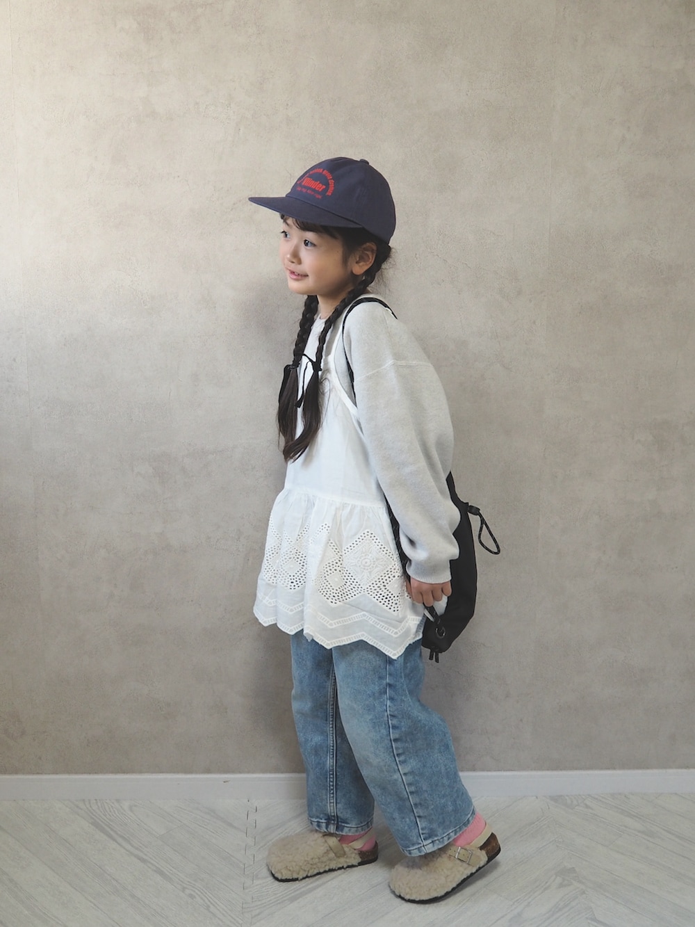 ホワイト系のニット/セーター、ホワイト系のサンダル、ブラック系のバックパック/リュックを着用したキッズの冬コーディネートの3枚目の写真