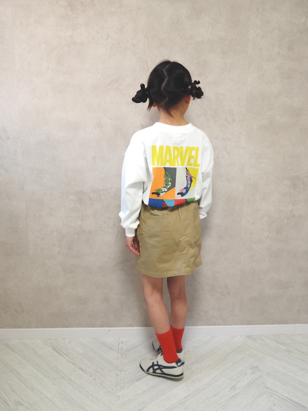 ベージュ系のスカート、ホワイト系のTシャツ/カットソー、ホワイト系のスニーカーを着用したキッズの冬コーディネートの3枚目の写真