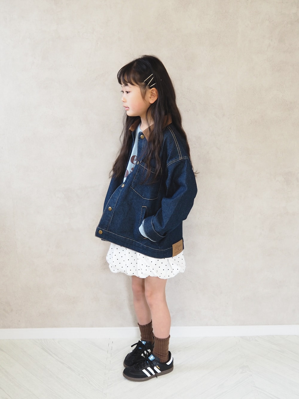 ブルー系のデニムジャケット、ホワイト系のスカート、ブラック系のスニーカーを着用したキッズの春コーディネートの3枚目の写真