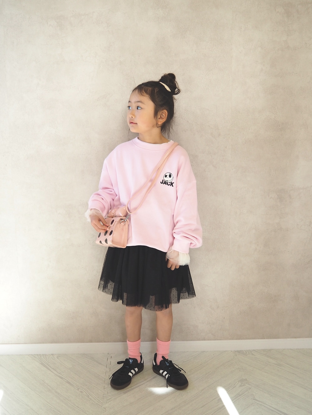 ピンク系のスウェット、ピンク系のショルダーバッグ、ブラック系のスカートを着用したキッズの冬コーディネートの2枚目の写真