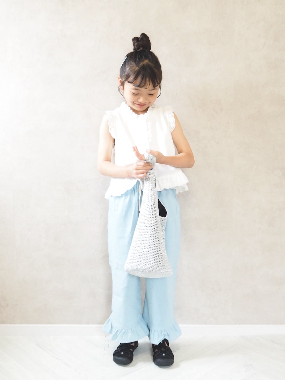 ブルー系のデニムパンツ、シルバー系のショルダーバッグ、ブラック系のサンダルを着用したキッズの夏コーディネートの2枚目の写真