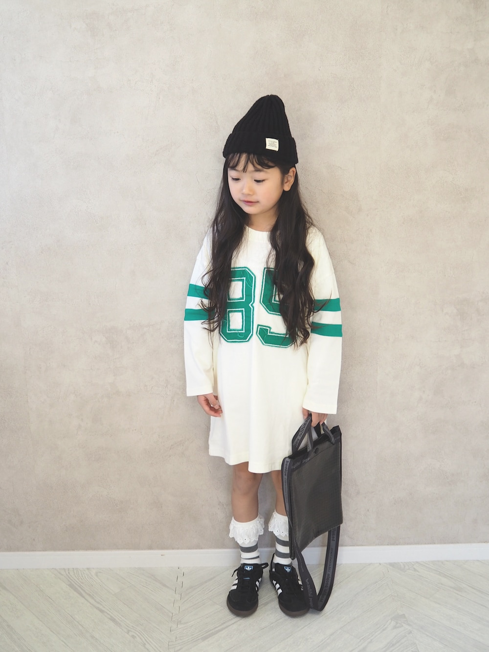 ブラック系のスニーカー、ホワイト系のワンピース、ブラック系のショルダーバッグを着用したキッズの冬コーディネートの4枚目の写真