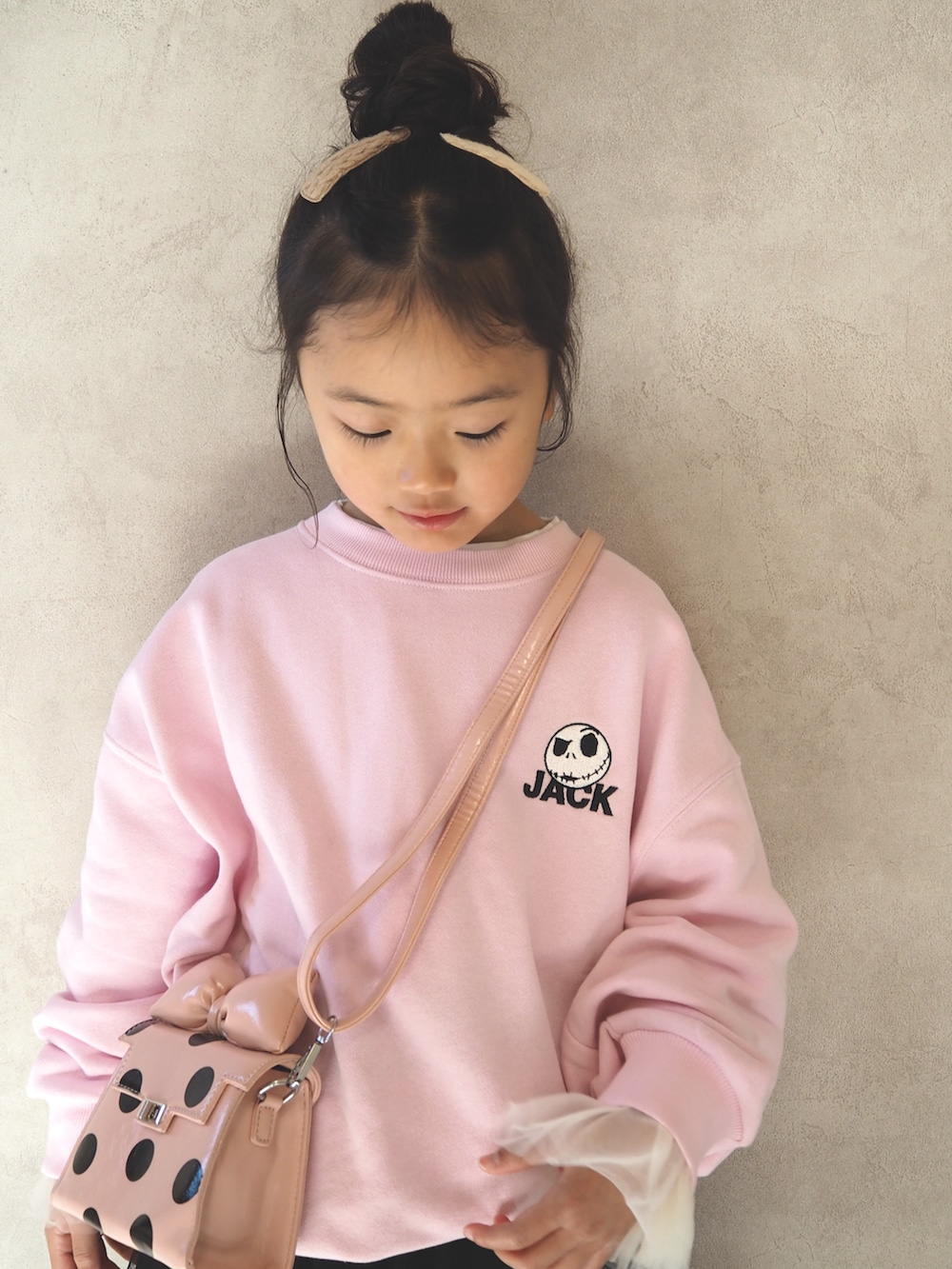 ピンク系のスウェット、ピンク系のショルダーバッグ、ブラック系のスカートを着用したキッズの冬コーディネートの5枚目の写真