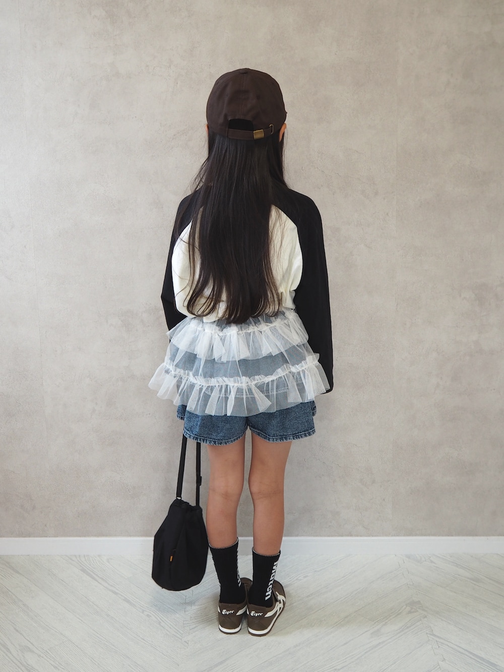 ホワイト系のスカート、ホワイト系のTシャツ/カットソー、ブルー系のデニムパンツを着用したキッズの秋コーディネートの4枚目の写真