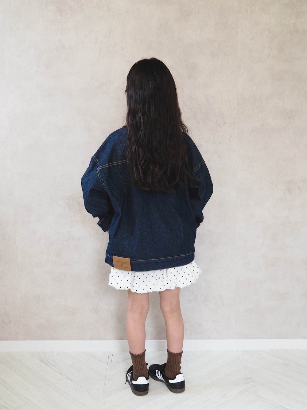 ブルー系のデニムジャケット、ホワイト系のスカート、ブラック系のスニーカーを着用したキッズの春コーディネートの4枚目の写真